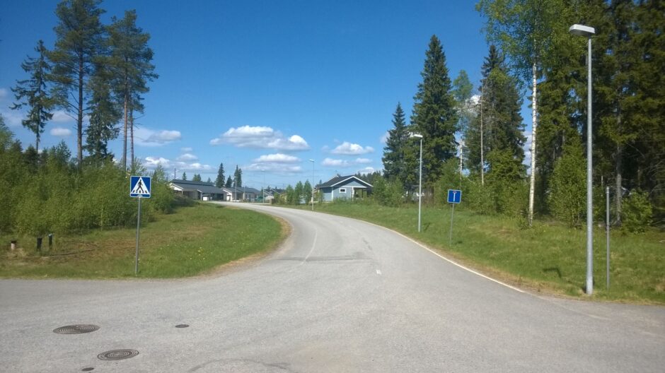 Ylämäkeen kaartuva omakotitaloalueen katunäkymä