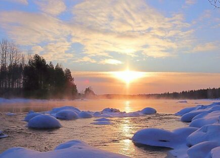 Talvinen järvimaisema ja auringon säteet pilvien raosta.