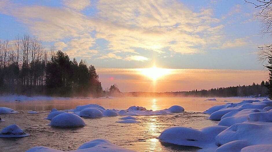 Talvinen järvimaisema ja auringon säteet pilvien raosta.