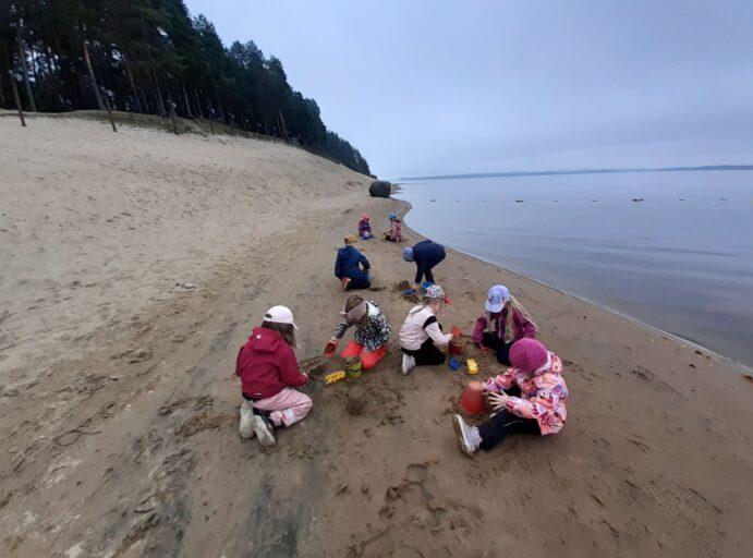 Maisemassa Hiukan hiekkarantaa, jossa lapsia leikkimässä hiekkaleikkejä.