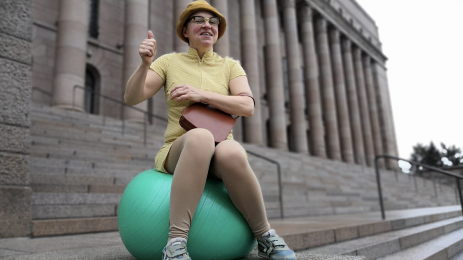 Tyyne Kettunen istuu jumppapallon päällä Eduskuntatalon edessä.