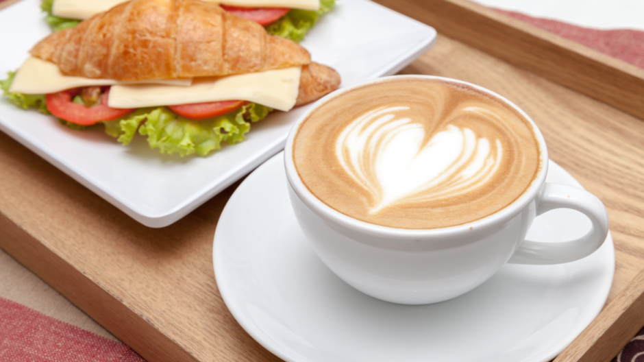 Erikoiskahvi ja täytetty croissant kahvilassa. Kuvituskuva.