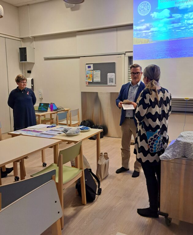 Kunnanjohtaja ojentamassa kiitokset koulunjohtaja Anu Rautiaiselle